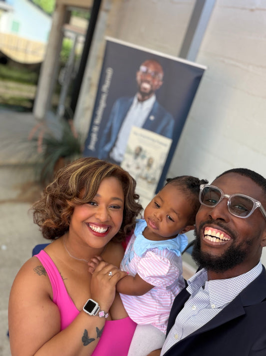 The Washington family of three stands in front of The Practicing Patient vendor booth at Black Writers Weekend.